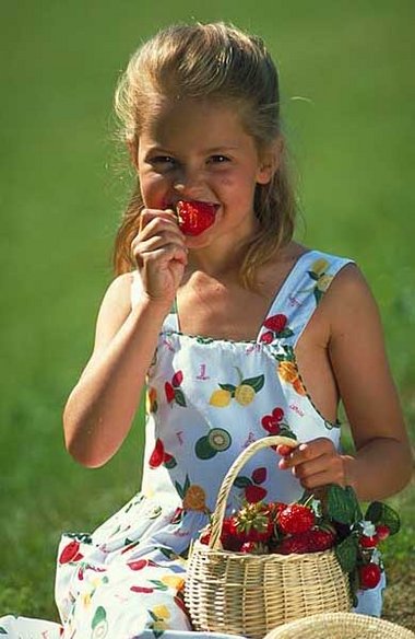Mädchen nascht Erdbeeren.